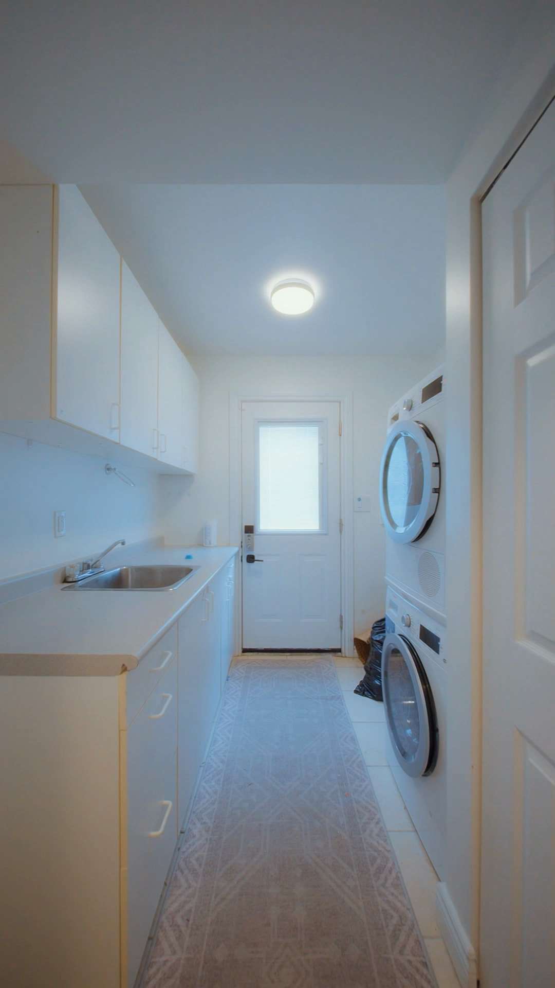 Before: a galley laundry with a counter and sink on one side and a stacked washer and dryer on the other.