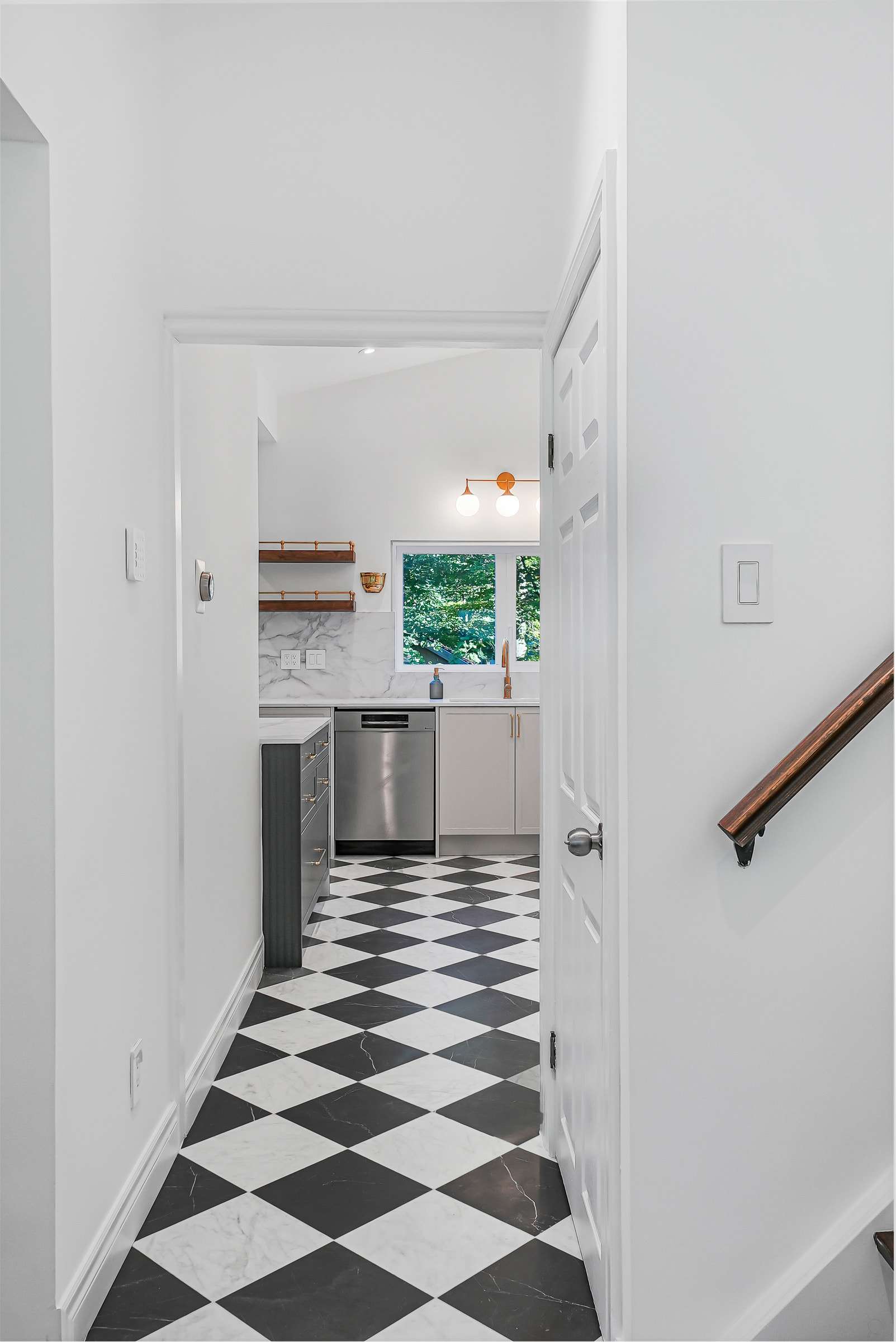The hall running into the kitchen, the black-and-white floor continuing through the doorway.