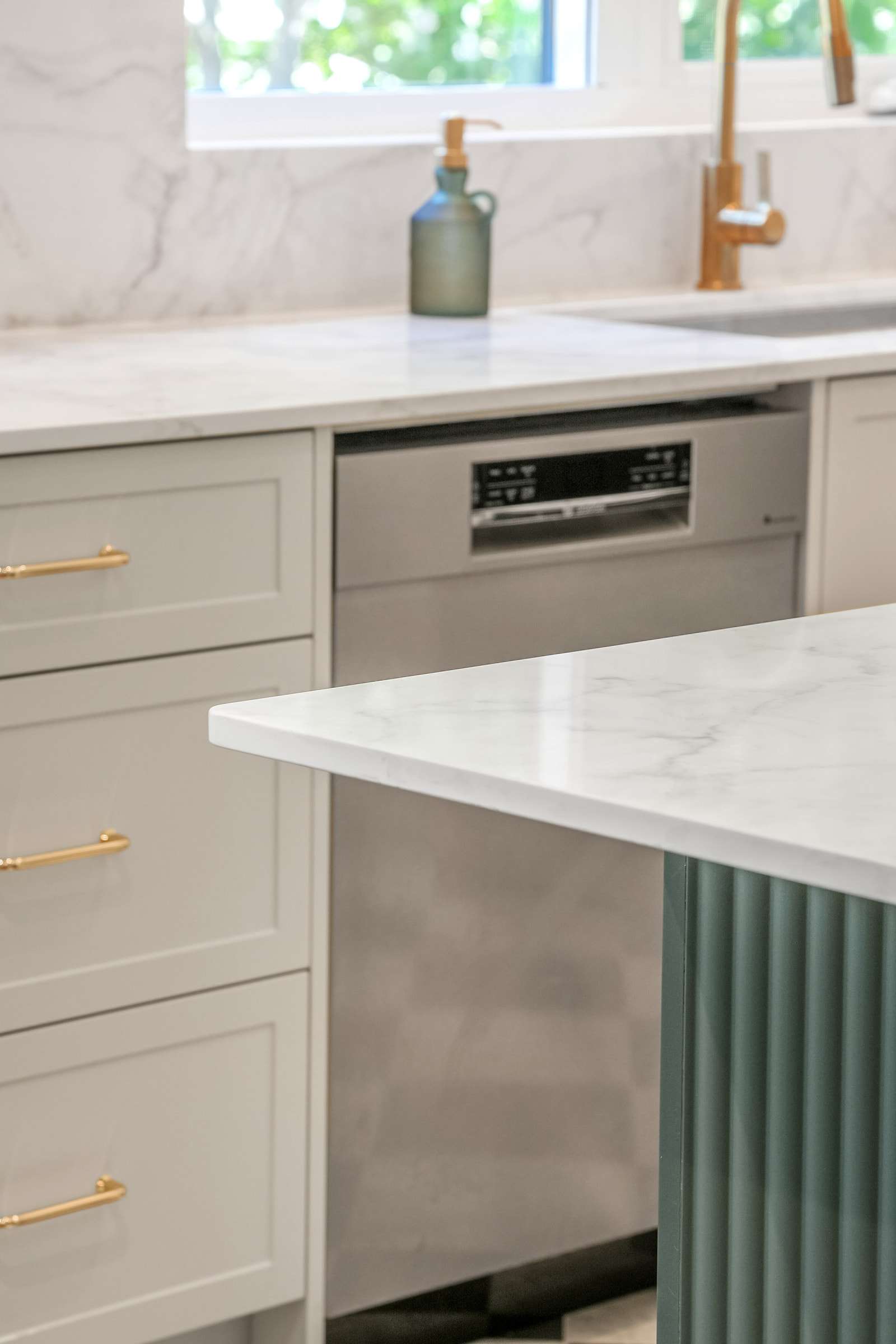 The fluted end of the island against the run of drawers and the dishwasher.