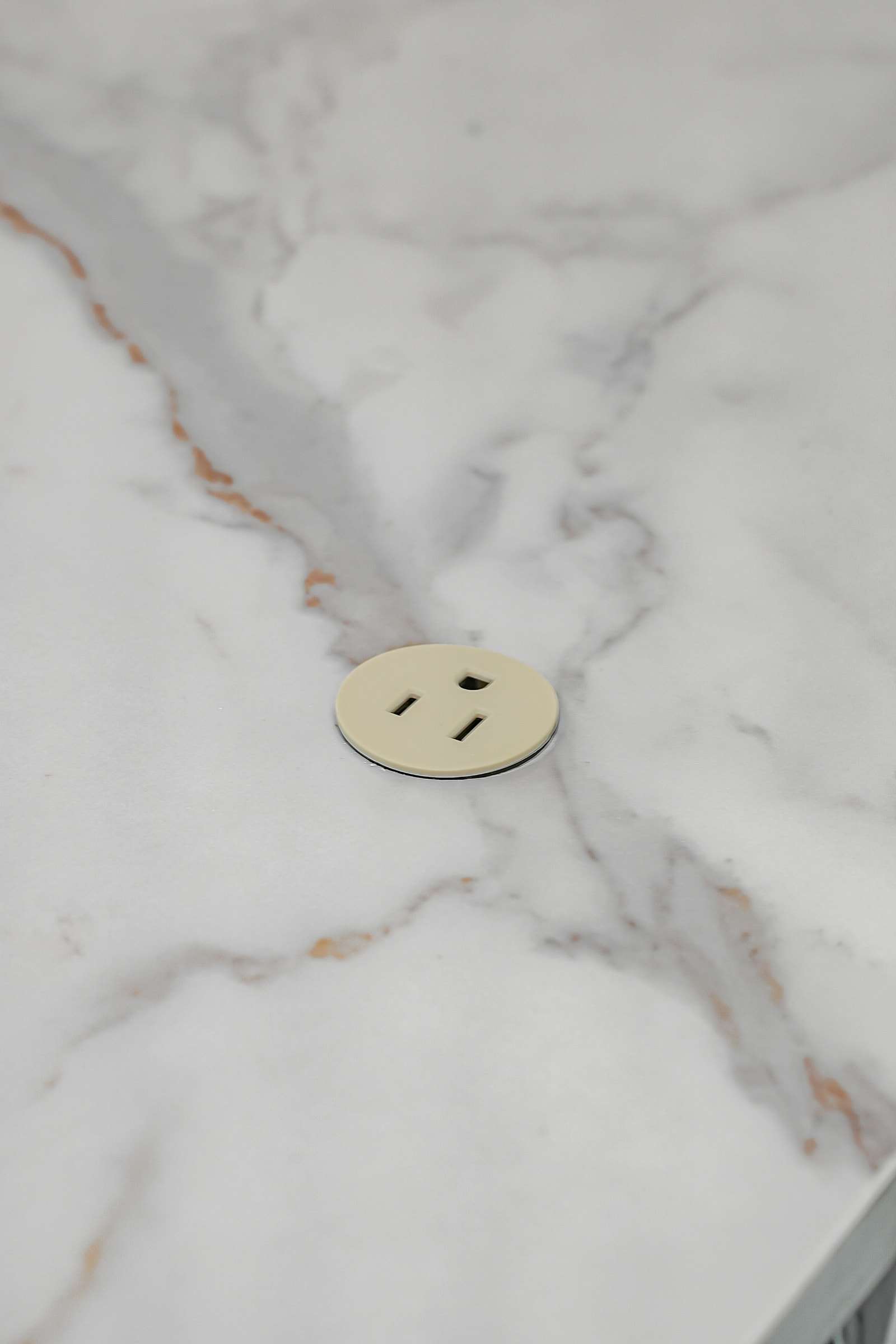 A round outlet set flush into the veined countertop.