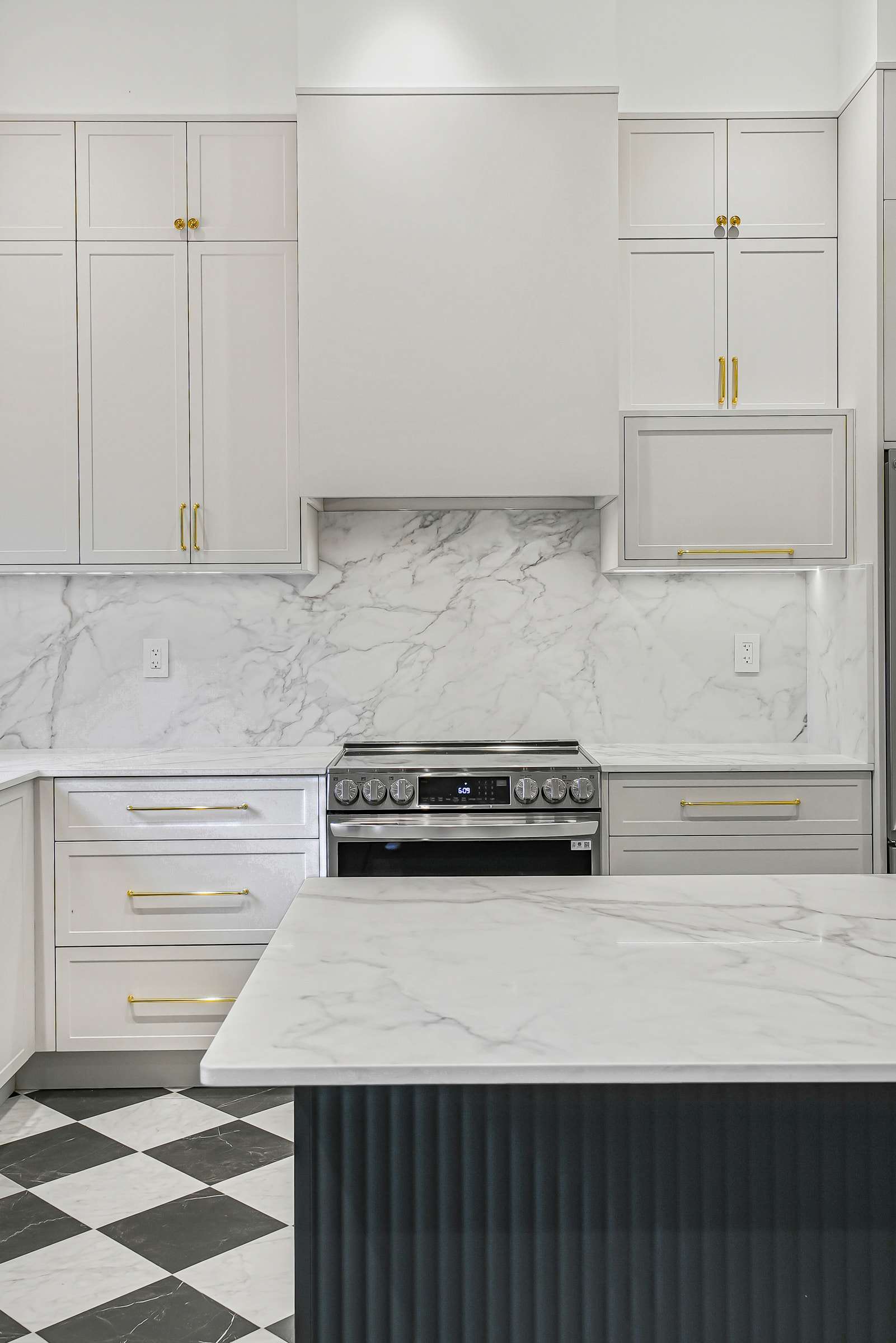 The range wall square on: cabinetry to the ceiling around a concealed hood, the island in front.