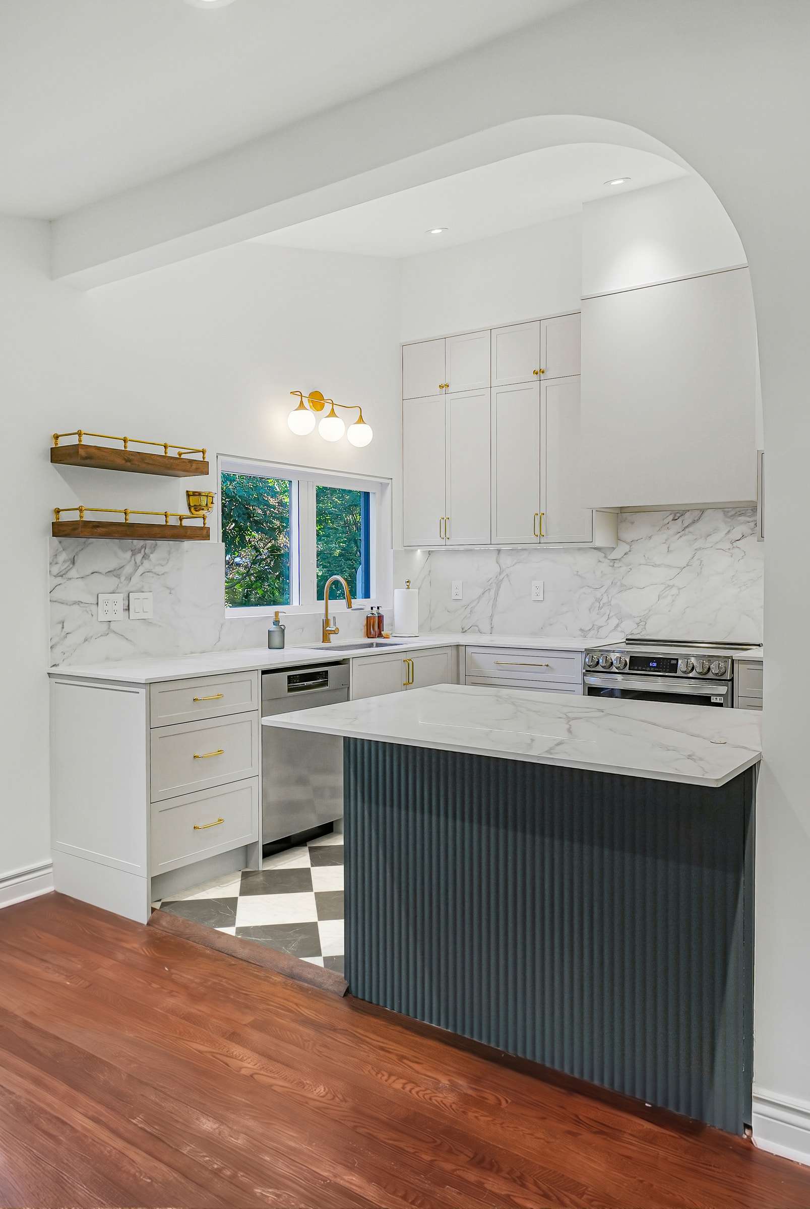 The kitchen seen through the wide arch from the adjoining room, the island in front of the sink wall.