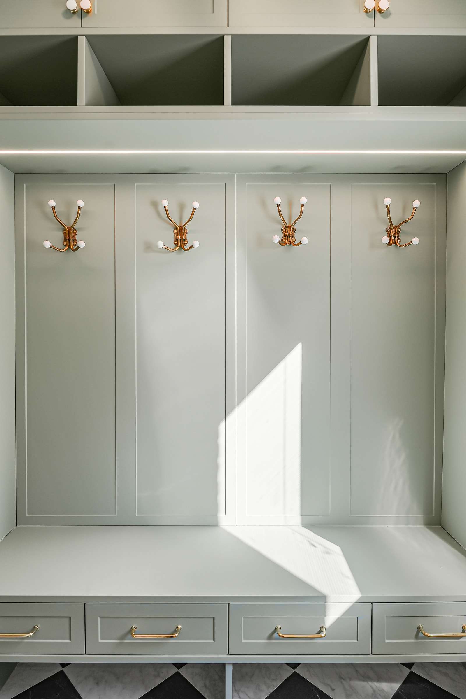 The mudroom bench square on: four hook panels, drawers below and cubbies above a light line.
