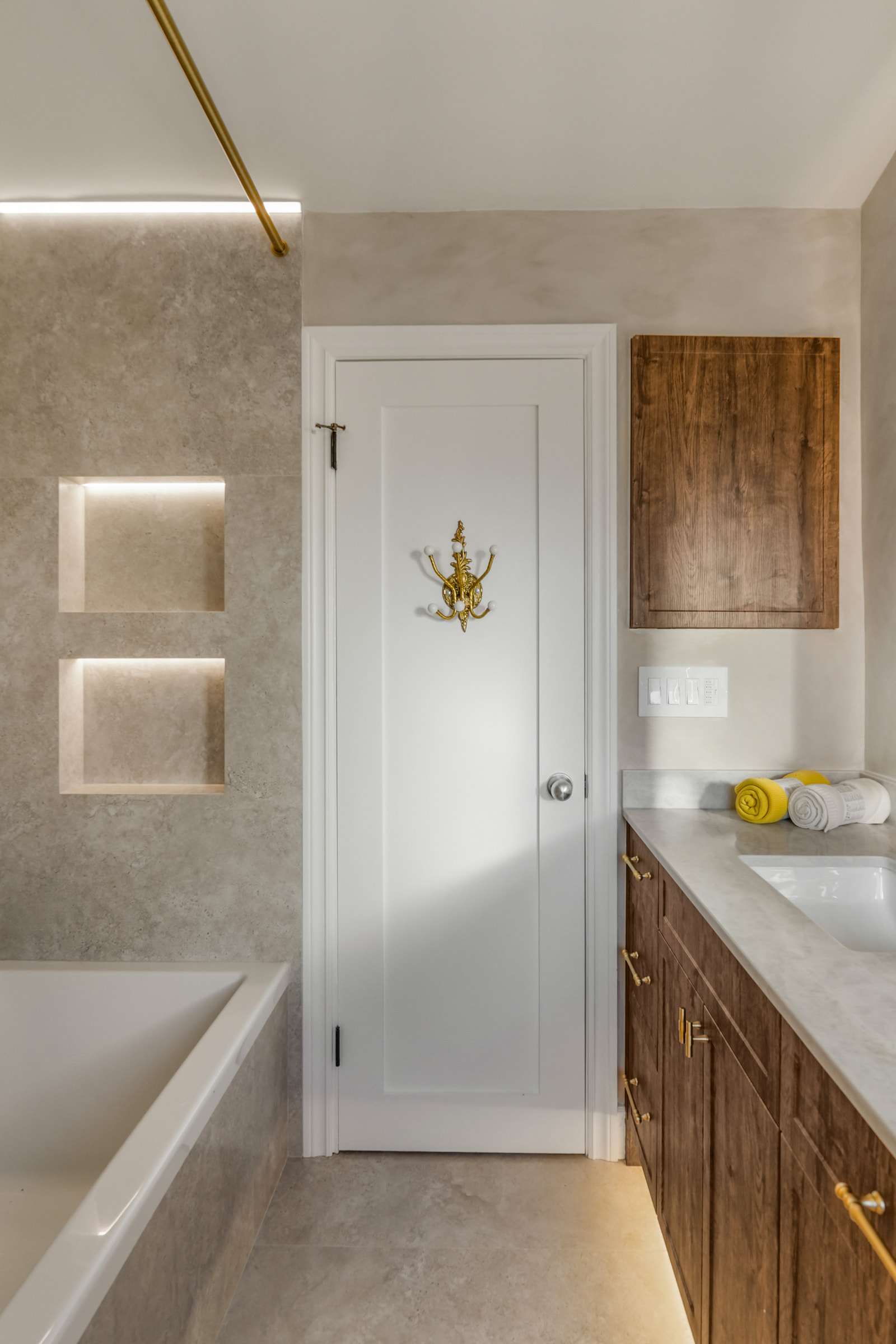 The tub with two lit niches above it, the door and the vanity alongside.