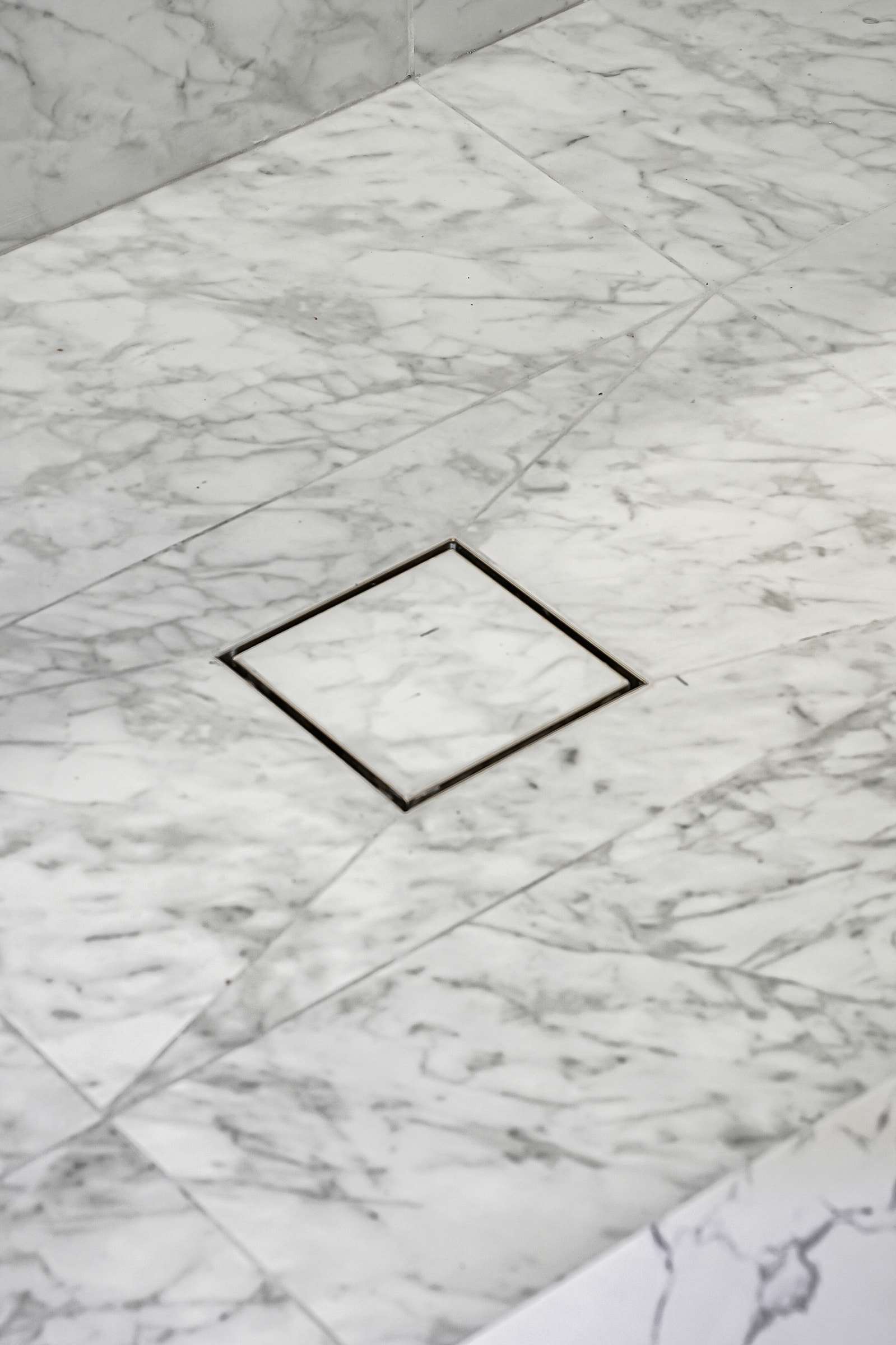 A square drain inside the shower, filled with tile, the floor tiles cut so the floor falls toward it.