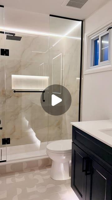 Completed bathroom with a framed glass shower, dark vanity and stone-look tile.