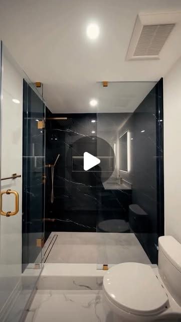 Completed bathroom with a black marble-look shower enclosure and brushed brass fixtures.
